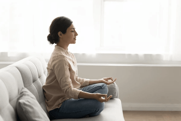 Jeune femme méditant dans son salon